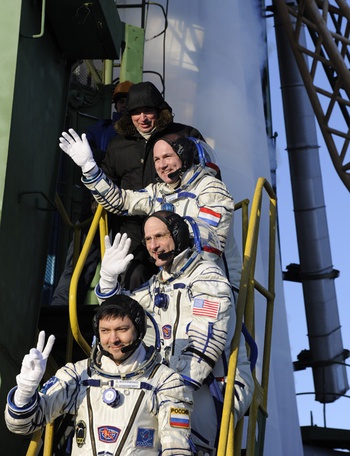 Russian cosmonaut Oleg Kononenko, NASA astronaut Don Pettit and ESA astronaut André Kuipers wave goodbye to the crowd gathered at the foot of the Soyuz launch pad stairs before taking the elevator to the top of the Soyuz rocket